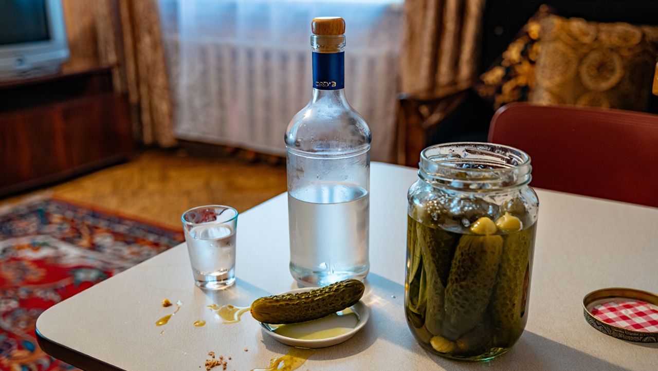Бутылка водки и соленве огурцы на столе